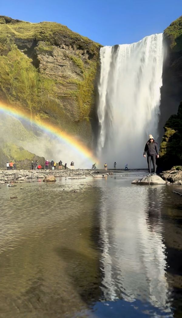 Skógafoss waterfall with a rainbow and its reflection