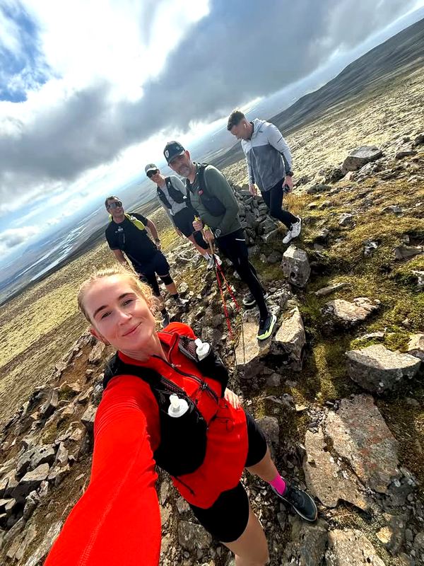 A runner and her group on a rocky mountain trail